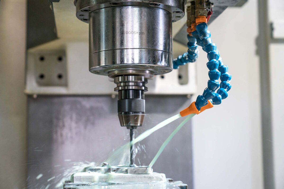 Nahaufnahme einer CNC-Maschine, die ein Metallteil mit Kühlmittel bearbeitet CNC-Fräsmaschine bei der Metallbearbeitung